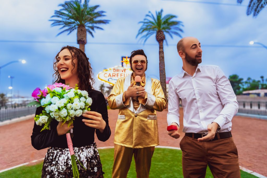 Couples celebrating vow renewal with bouquets at the Las Vegas sign