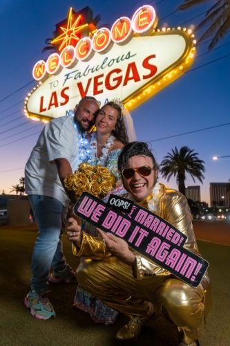 Couple celebrates with an Elvis impersonator and holds up a Las Vegas-themed sign at the Welcome to Fabulous Las Vegas sign.