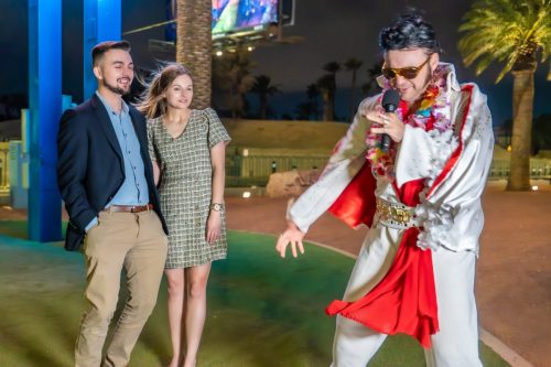 Groom shakes hands with gold-suited Elvis impersonator during their Las Vegas sign wedding.